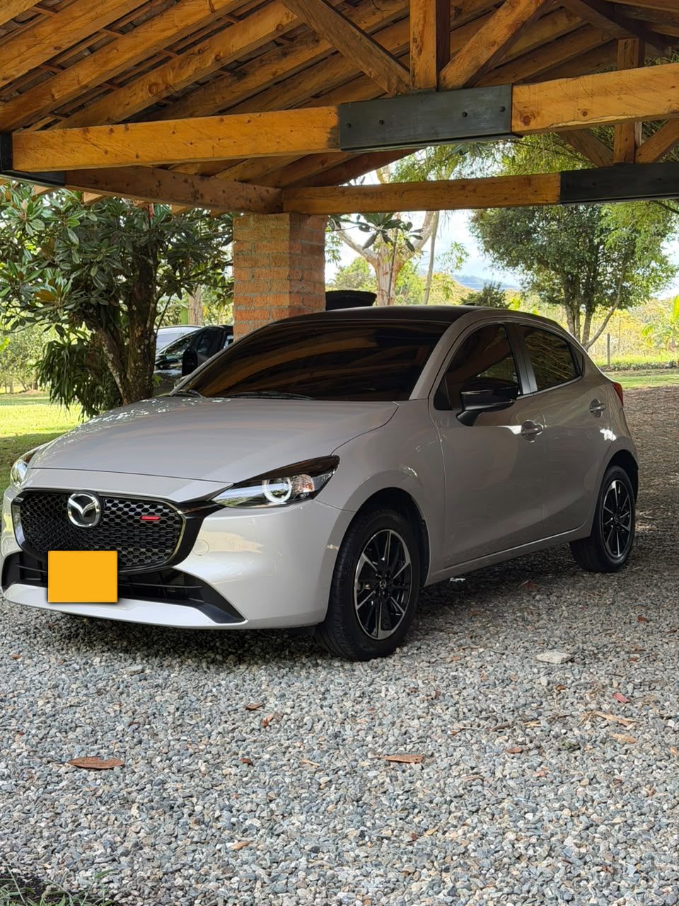 Mazda 2 plateado bajo un kiosco de madera